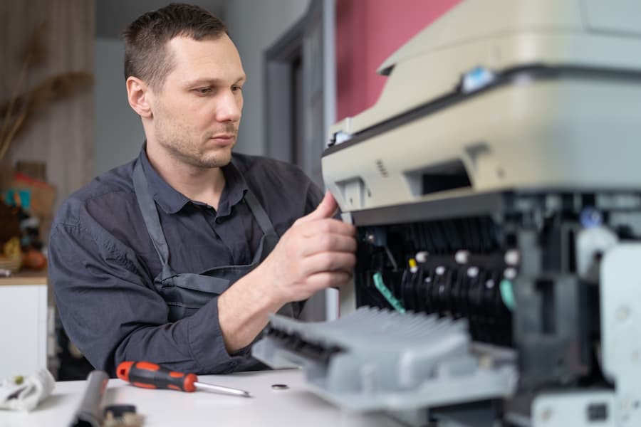 Copier technician performing maintenance and repair on office equipment